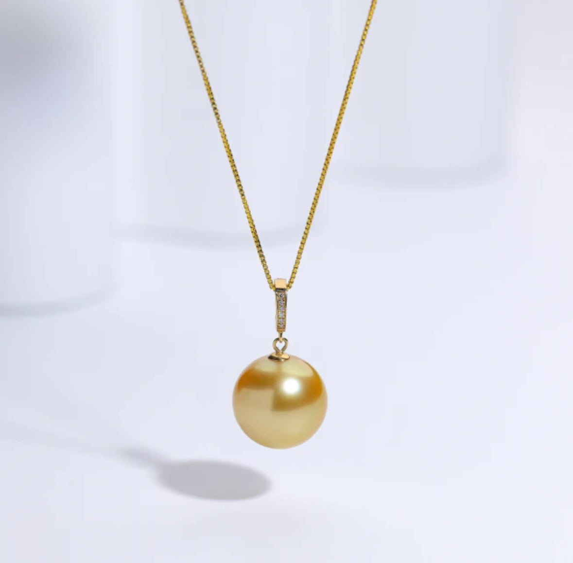 The South Sea Gold pearl with a 12-13mm,Round Sharp without flaws, set in a diamond accent pendant 18k clasp