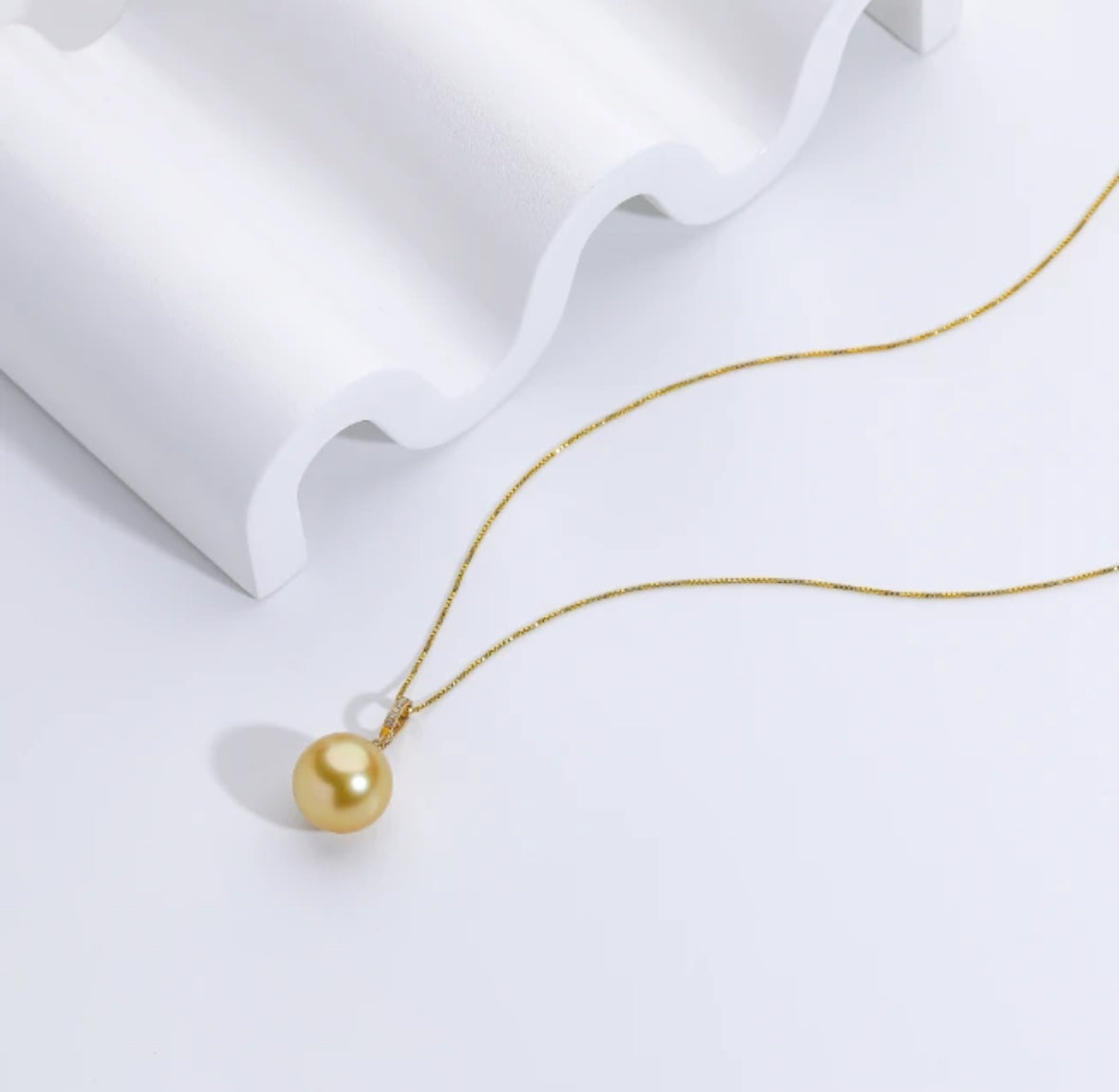 The South Sea Gold pearl with a 12-13mm,Round Sharp without flaws, set in a diamond accent pendant 18k clasp